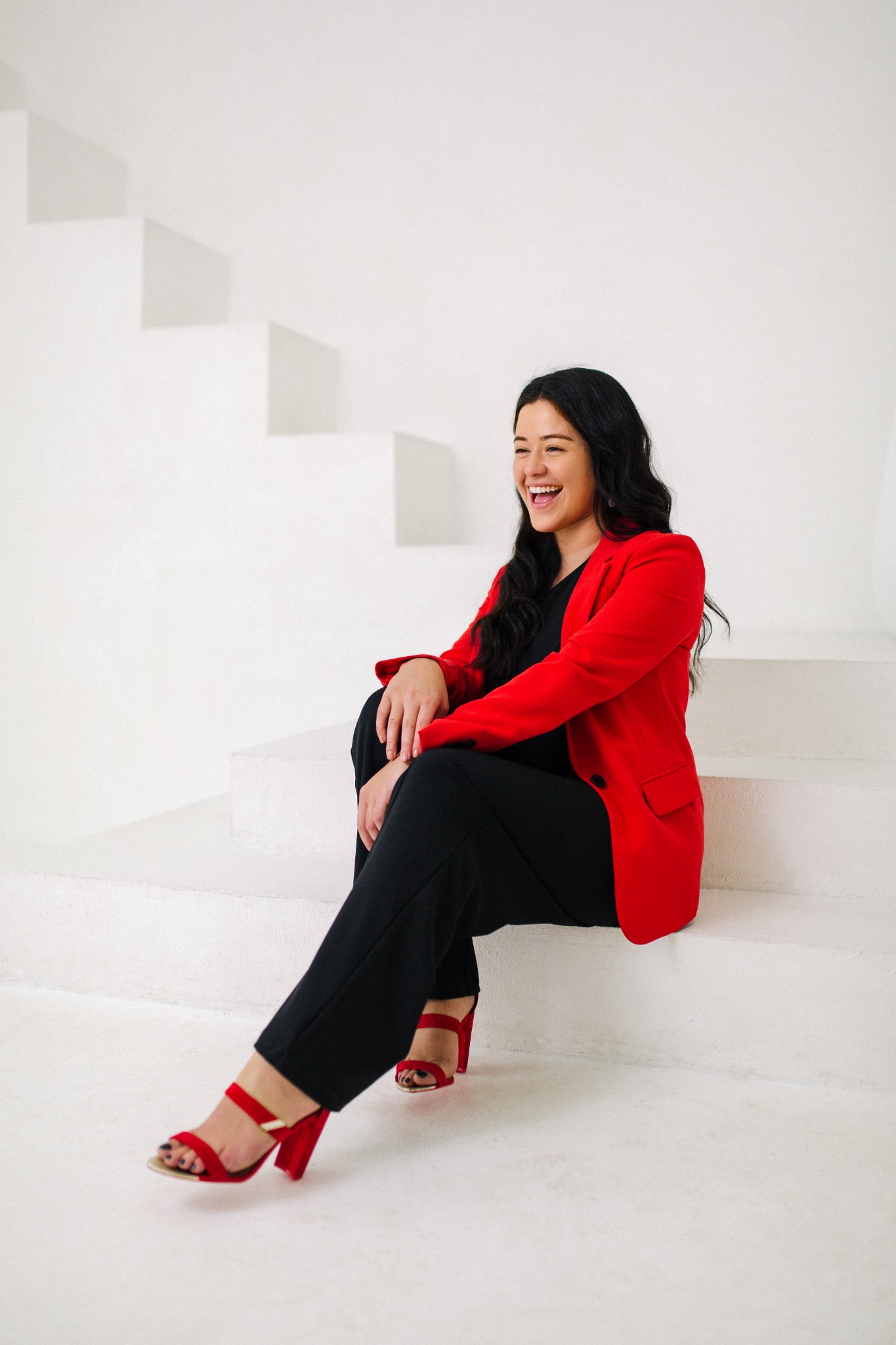 Francesca Vaccarello seated on a white staircase wearing a red blazer